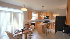 A modern kitchen with wooden cabinets, a central island, and a dining area with chairs. - Spacious and comfortable 5 bedroom, 2 1/2 bath two miles from down town Geneva (Geneva)