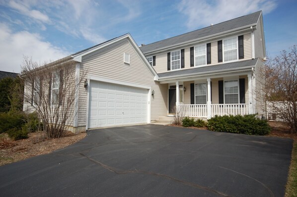 A two-story house with a garage, a front porch, and a driveway.