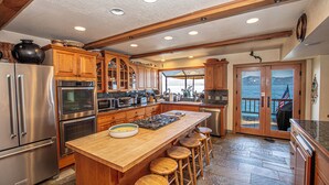 Una cocina amplia con una isla grande, electrodomésticos de acero inoxidable, armarios de madera y vistas al exterior.