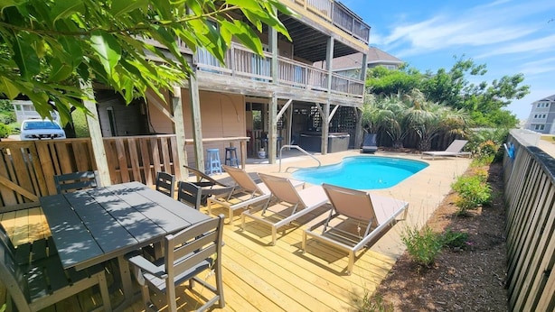 A wooden deck with a pool, lounge chairs, and a table. - 5BR Corolla Light retreat with pool, hot tub & beach access. CL-134 (Corolla)
