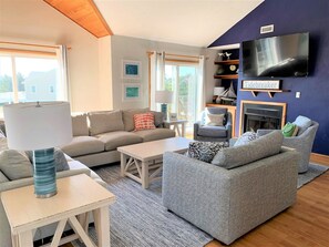A living room with a sofa, a coffee table, a TV, and a fireplace.