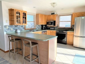 A kitchen with wooden cabinets, a stainless steel refrigerator, a microwave, an oven, and a coffee maker. - 5BR Corolla Light retreat with pool, hot tub & beach access. CL-134 (Corolla)
