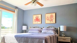 A bedroom with a bed, two bedside tables with lamps, a ceiling fan, and two framed pictures on the wall. - 5BR Corolla Light retreat with pool, hot tub & beach access. CL-134 (Corolla)