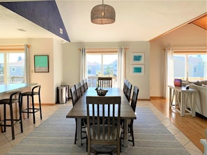 A dining area with a long table, chairs, and a hanging light fixture. - 5BR Corolla Light retreat with pool, hot tub & beach access. CL-134 (Corolla)