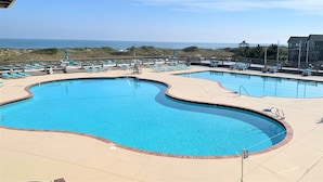 A swimming pool with a curved edge, surrounded by lounge chairs and a gazebo. - 5BR Corolla Light retreat with pool, hot tub & beach access. CL-134 (Corolla)