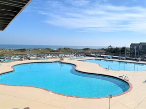 A swimming pool with a curved edge, surrounded by lounge chairs and a gazebo.