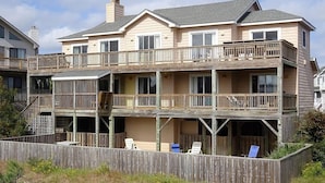 A multi-story beachfront property with a balcony, outdoor seating, and a wooden deck. - 5BR Corolla Light retreat with pool, hot tub & beach access. CL-134 (Corolla)