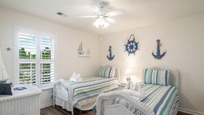 Quarto com duas camas, um ventilador de teto e decoração náutica.