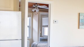 A room with a bed, a white refrigerator, a ceiling fan, and a couch with a cushion. - Private Beach Front Cottage unit 3 (Ft Pierce)