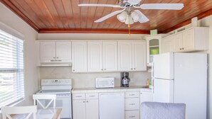 A kitchen with white cabinets, a microwave, a stove, a dishwasher, and a ceiling fan. - Private Beach Front Cottage unit 3 (Ft Pierce)