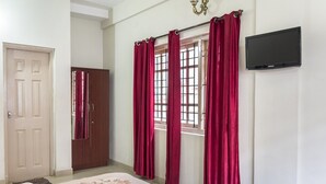 A bedroom with a bed, a wardrobe, a window with curtains, and a flat-screen TV on the wall. - GuestHouser 3 BHK Cottage 563f (Ootacamund)