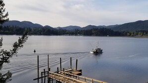 Un lago con un muelle que se adentra en el agua, rodeado de montañas y árboles.