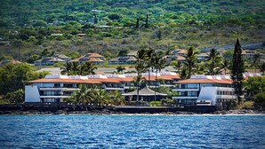 Un hotel frente al mar con varias edificaciones y abundante vegetación en el fondo.