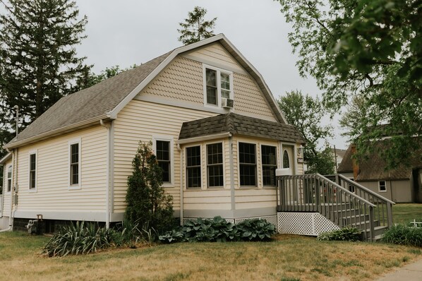 A single-story house with a gabled roof, a front porch, and a small staircase leading to the entrance.