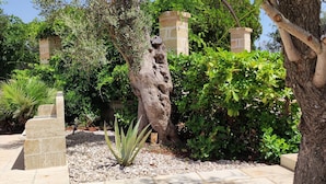 A garden with a stone pillar, a tree, and various plants.