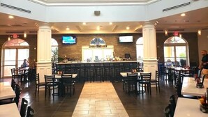 A spacious restaurant with a central bar, multiple seating areas, and a high ceiling.
