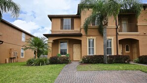 A two-story residential building with a brick pathway leading to the entrance.