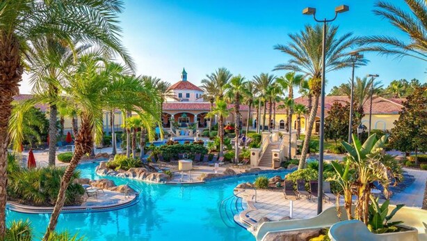 A resort with a large pool, palm trees, and a building with a red roof.
