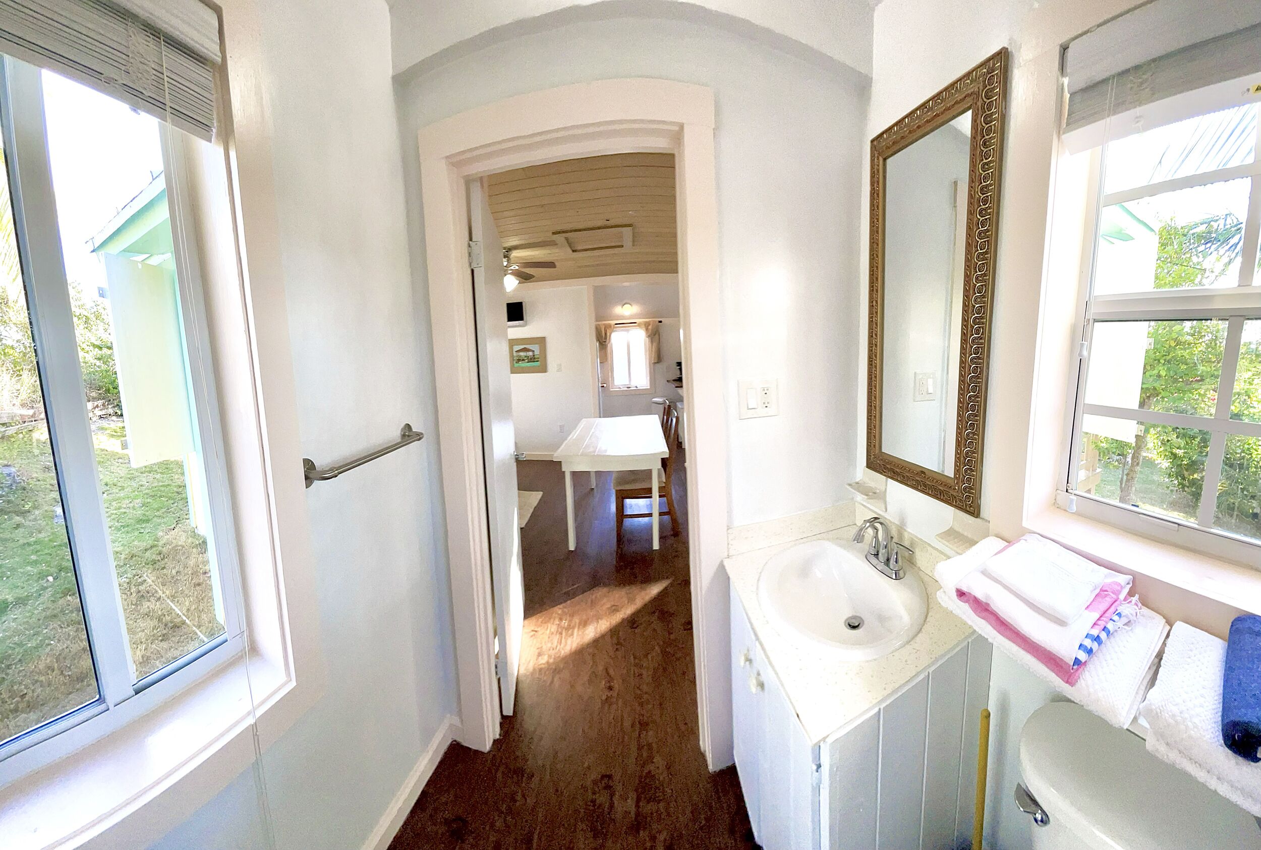 A narrow hallway leading to a bathroom with a sink, mirror, and towel rack.