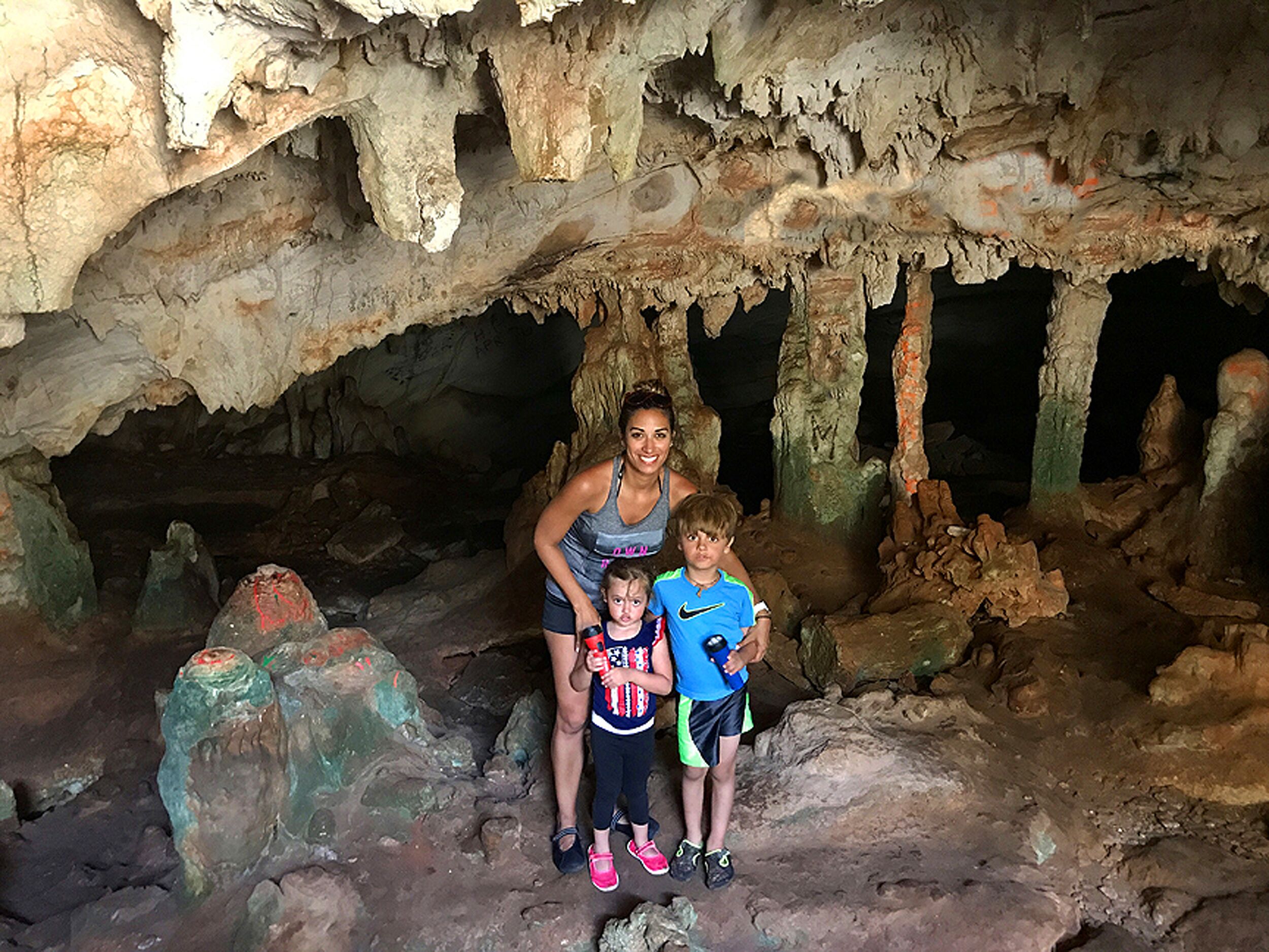 Une famille se trouve à l’intérieur d’une grotte, entourée de stalactites et de stalagmites.