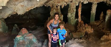 Une famille se trouve à l’intérieur d’une grotte, entourée de stalactites et de stalagmites.