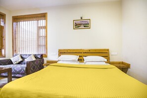 A bedroom with a wooden bed, a sofa, and a window with blinds. - GuestHouser 1 BR Cottage 4e68 (Manali)
