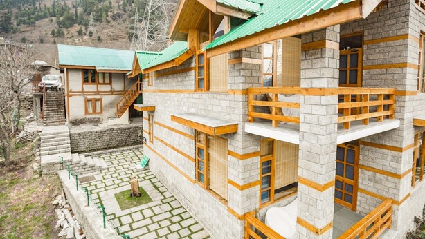 A multi-story building with a stone facade and wooden balconies. - GuestHouser 1 BR Cottage 4e68 (Manali)