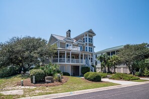 A two-story house with a balcony, a chimney, and a well-maintained lawn. - Legasea DeBordieu Home LegaSea Spectacular porches Close to Beach (Georgetown)