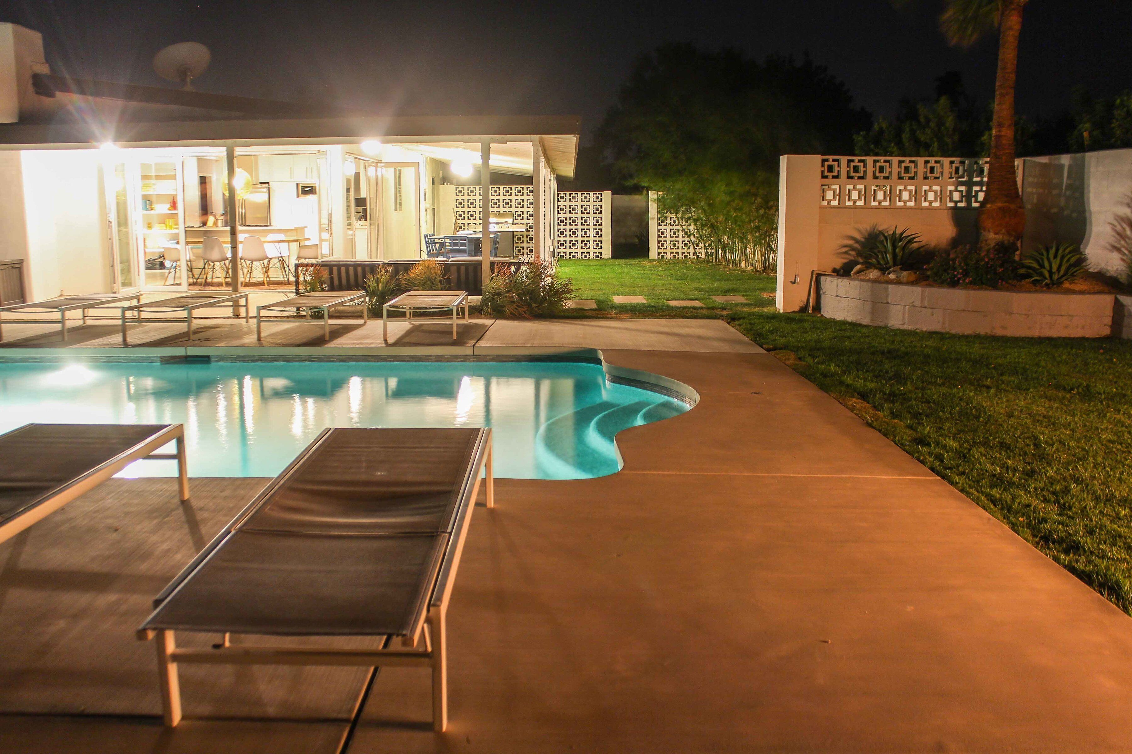 Piscina com espreguiçadeiras e um espaço de estar ao ar livre.