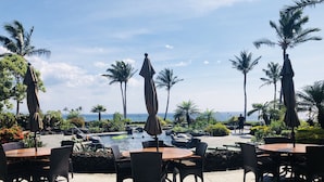 Un espace aménagé au bord de la piscine, avec des sièges extérieurs et une vue sur l’océan.