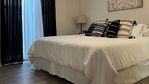 Ett sovrum med en säng, en takfläkt, en vägglampa och ett konstverk med blommotiv.
