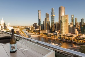 A bottle of wine and two glasses on a table with a cityscape view. - Flinders Luxury Penthouse (Melbourne)