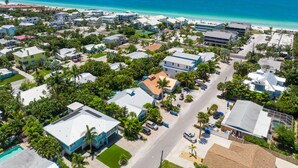 Vista aérea de uma área residencial costeira com casas, ruas e uma praia.