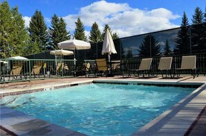 Relax by the clear pool surrounded by lounge chairs and umbrellas.