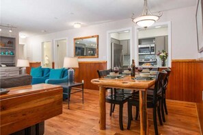 Cozy living and dining area with a dining table for four, sofa, armchairs, and a large mirror.