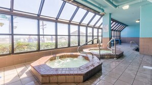 A large indoor swimming pool with two hot tubs, a tiled floor, and a view through large windows. - Phoenix V 202 (Orange Beach)