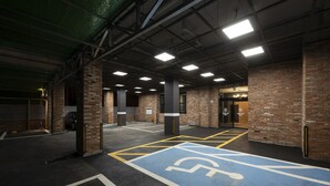 Un estacionamiento interior con paredes de ladrillo, un espacio reservado para discapacitados de color azul y una línea amarilla delimitando.