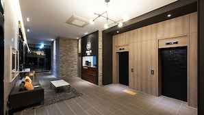Un vestíbulo de hotel moderno con mostrador de recepción, zona de estar y ascensores.