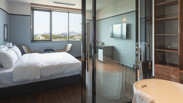 Un dormitorio moderno con una cama grande, un ventanal que da al baño y vistas a la ciudad.