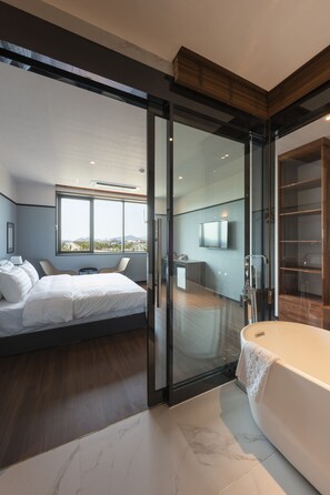 Un dormitorio moderno con una cama grande, un ventanal que da al baño y vistas a la ciudad.