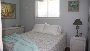 Une chambre à coucher comprenant un lit, une table de chevet, une lampe, une fenêtre et des éléments décoratifs sur les murs.