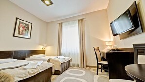 A hotel room with two beds, a desk, a chair, a TV, and a window with curtains. - Picaro Krasnik Dolny (Boleslawiec)