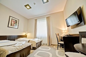 A hotel room with two beds, a desk, a chair, a TV, and a window with curtains. - Picaro Krasnik Dolny (Boleslawiec)