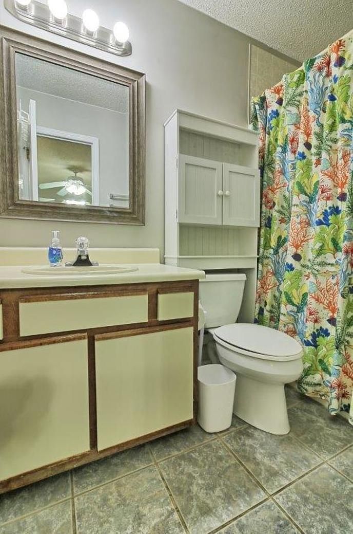 Une salle de bain équipée d’un lavabo, d’un miroir, de toilettes et d’un rideau de douche.