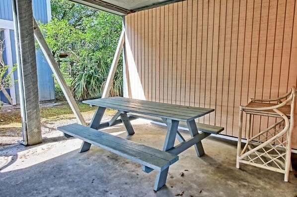 A picnic table and a wicker chair under a wooden structure. - "The Beverly" Updated Beach House. Steps from the beach! August Availability (Murrells Inlet)