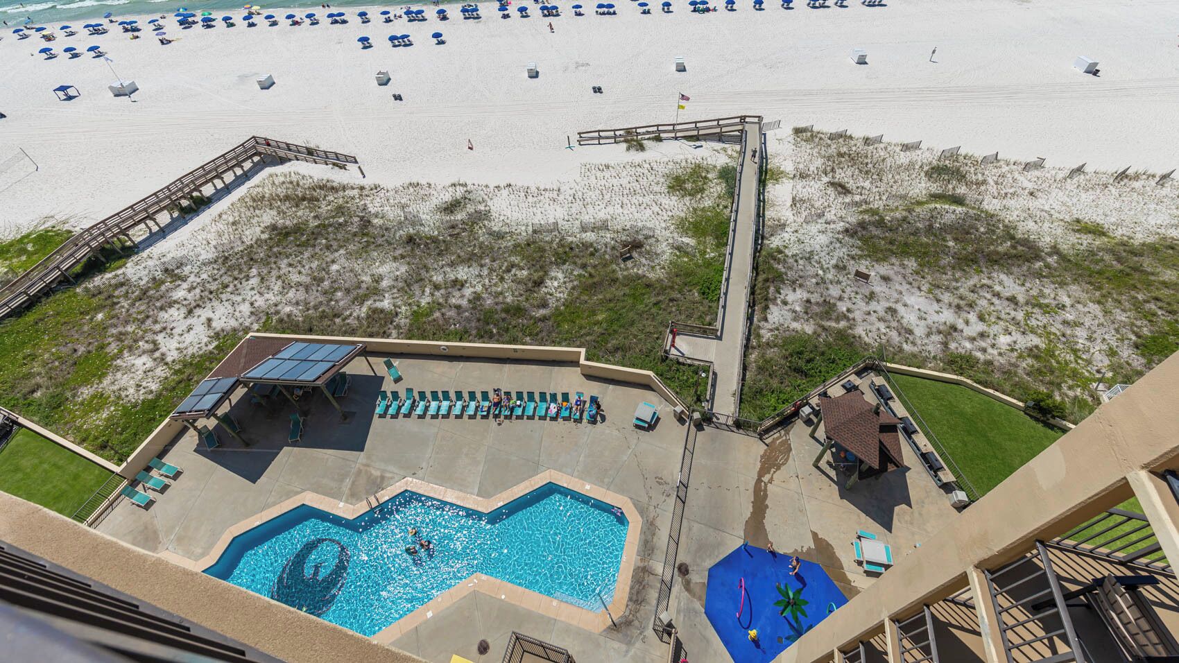 A rooftop pool with a view of the beach, lounge chairs, and a lifeguard stand.
