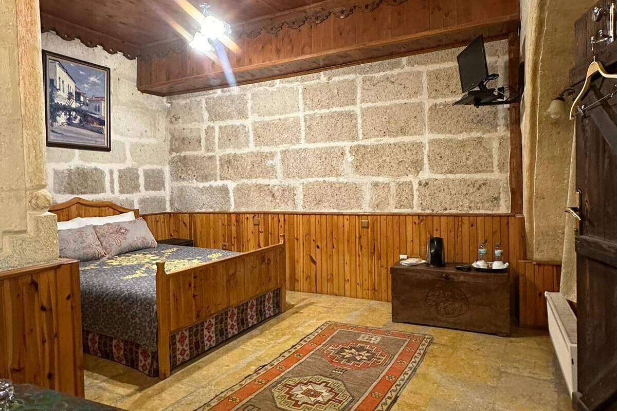 A rustic room with a stone wall, wooden bench, and a bed with a patterned bedspread.