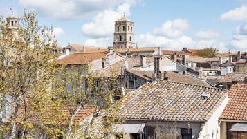 A historic town with terracotta-tiled rooftops, a prominent bell tower, and traditional architecture.