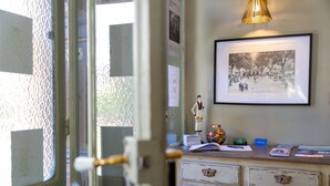 Ein Zimmer mit einem Möbelstück im Vintage-Stil, einem gerahmten Foto an der Wand und einer Tür mit Messinggriffen.