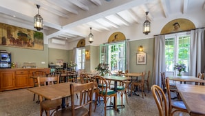 Ein Restaurant mit Holztischen und -stühlen, einer Bar und Kunstwerken an den Wänden.